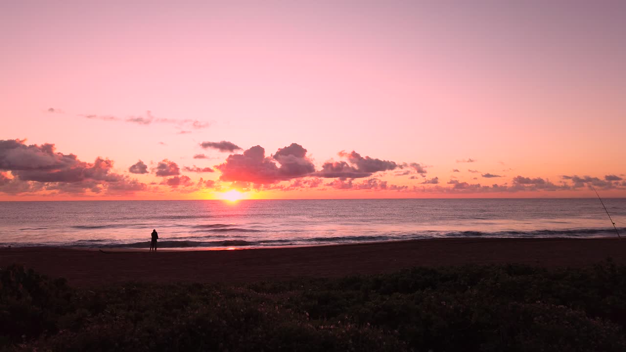 UHD Hawaii Kauai static of couple in distance on beach watching partly cloudy sunrise.  Part four of five, also available as five clips in timelapse