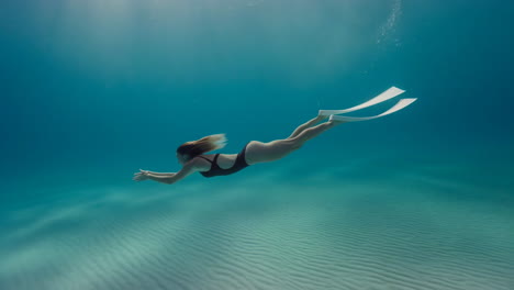 woman free-diving in clear blue ocean waters