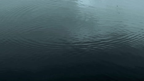 dark color tone of close up rain water drop falling to the river surface in rainy season , 4k dci resolution