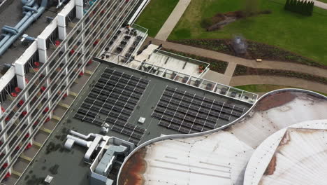 solar panels on rooftop of hotel building, aerial drone ascend view