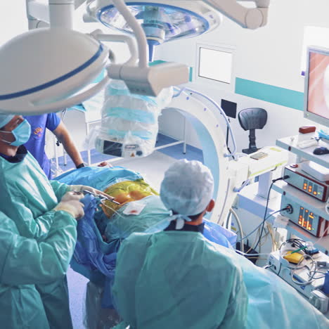 group of surgeons perform operation while looking at monitor. operating process by specialists wearing protective clothing. modern technologies during the operation in medical clinic.