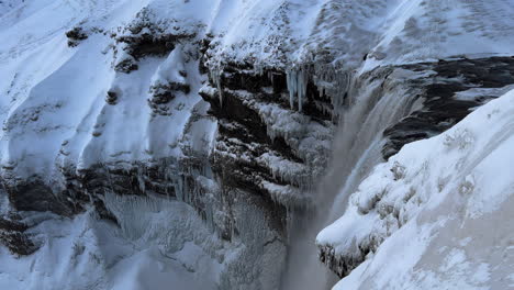 Seljalandsfoss-Waterfall-in-Winter-Iceland,-Slow-Motion-View-of-the-Cascade-of-the-Falls-and-Water-Flow-from-a-Tall-Rocky-Snowy-Frozen-Cliff,-Famous-Tourist-Destination-Site