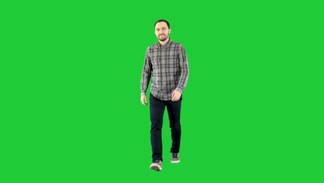 smiling young man is walking on a green screen, chroma key