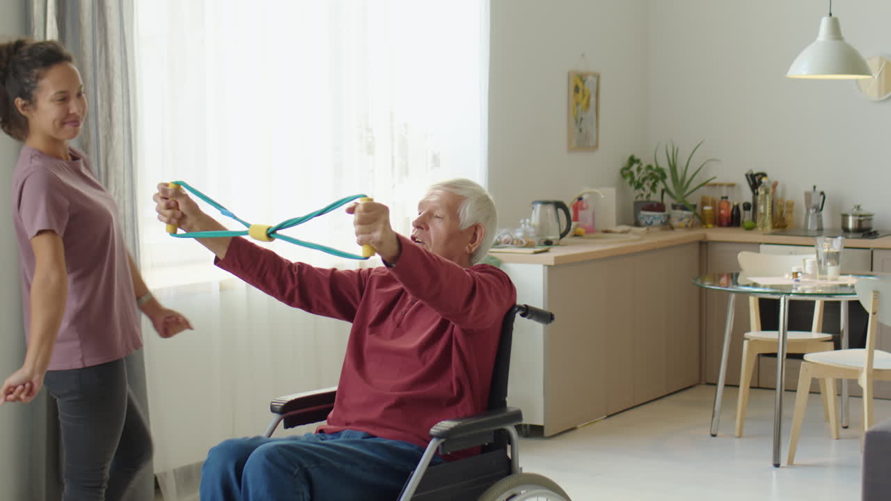 Eldelrly Man in Wheelchair Exercising with Help of Caregiver