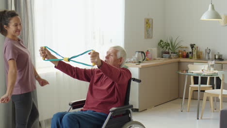 eldelrly man in wheelchair exercising with help of caregiver