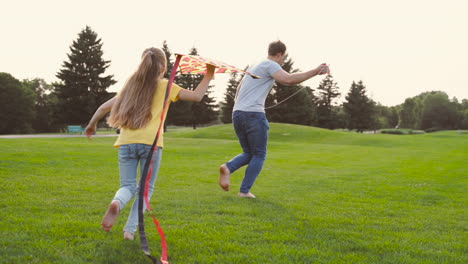 Dad-Flying-A-Kite-While-Running-With-His-Little-Daughter-On-Meadow