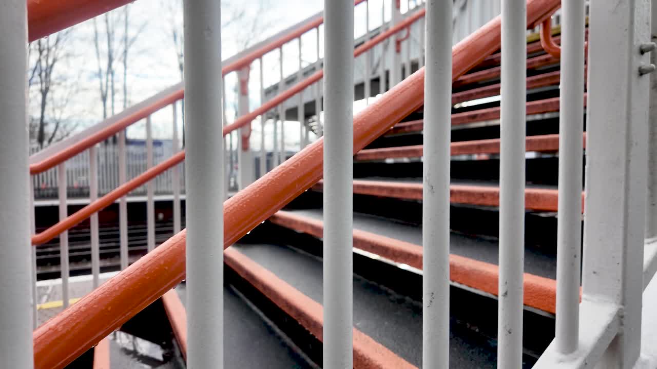 Grades metálicas laranjas e brancas na estação de Anerley, London Overground, com degraus e plataforma adequados para temas de transporte e urbanos