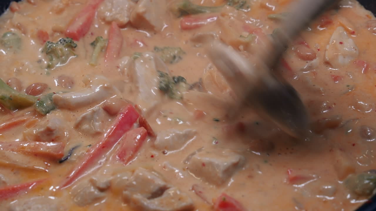el curry de pollo y verduras rico y cremoso hierve en una sartén caliente en la estufa