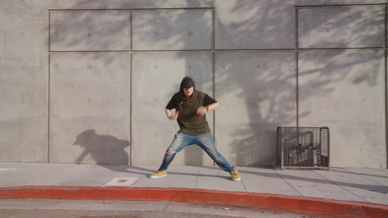 Uomo che balla hip hop freestyle lungo il marciapiede cittadino