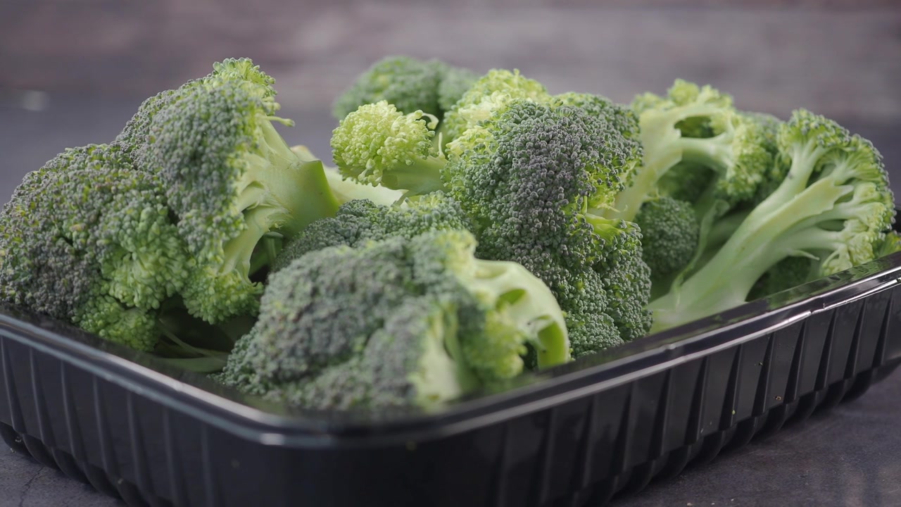 Cimette di broccoli freschi in un vassoio di plastica nero