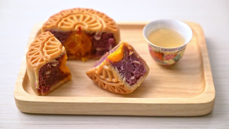 chinese moon cake purple sweet potato and egg yolk flavour with tea on wood plate