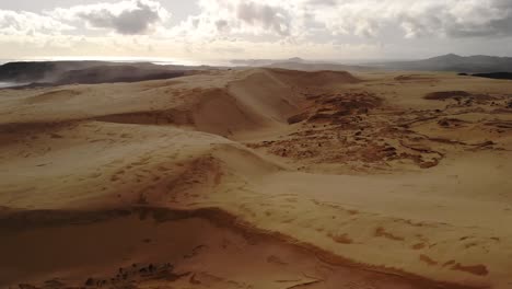 huge sand dunes scenery at shore, aerial sideway shot, partly cloudy day