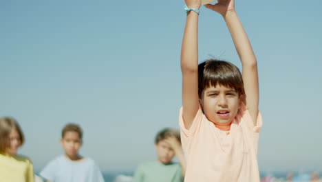 Happy-teen-soccer-team-captain-standing-on-beach-with-ball