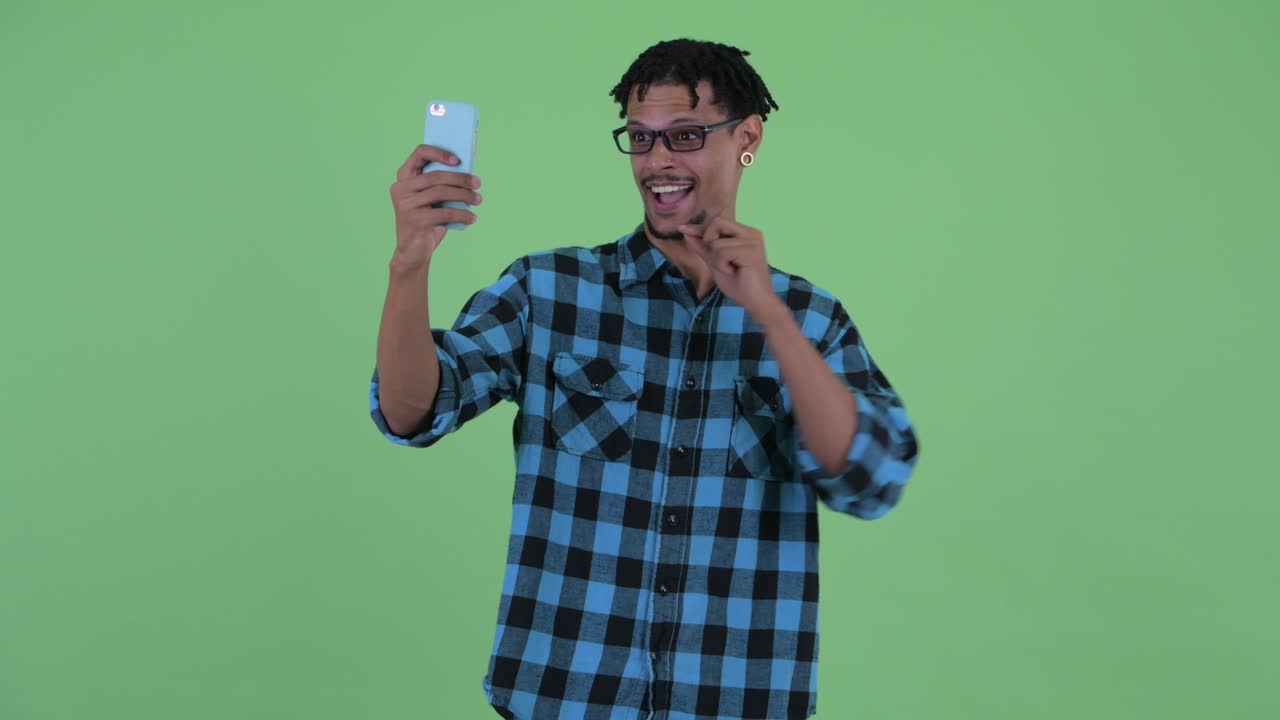 Happy young handsome African hipster man using phone