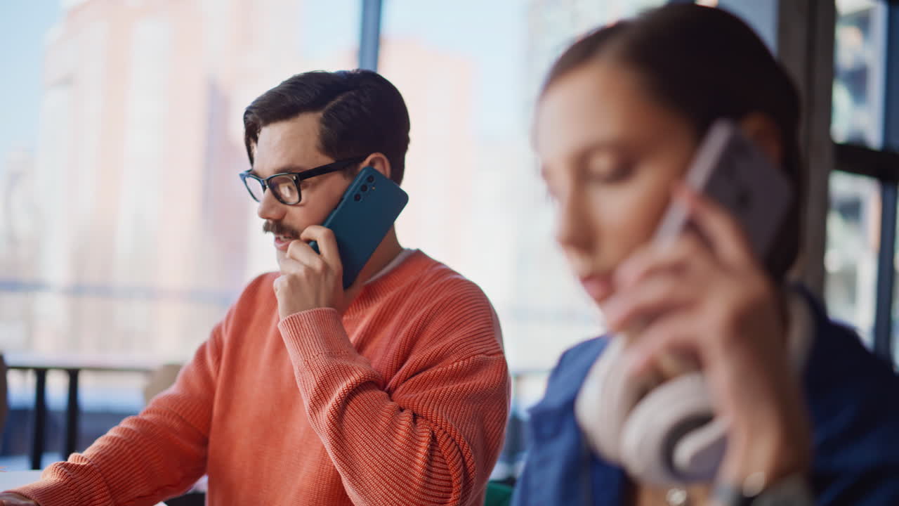 Company coworkers speaking cellphones at workplace closeup. Two professional
