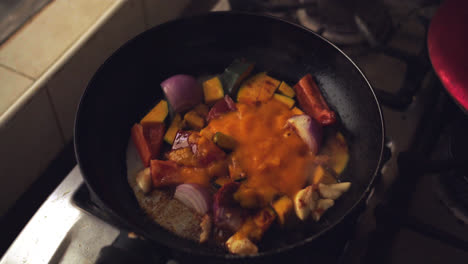 frying onion, tomato, chili and "zapallo loche" in a pan