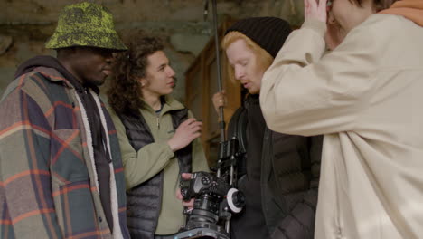 Close-Up-View-Of-A-Production-Team-And-Cameraman-Laughing-While-Reviewing-A-Scene-In-A-Camera-In-A-Ruined-Building-1