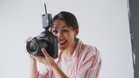 Female-Photographer-With-Camera-On-Photo-Shoot-Against-White-Studio-Backdrop