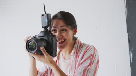 female photographer with camera on photo shoot against white studio backdrop