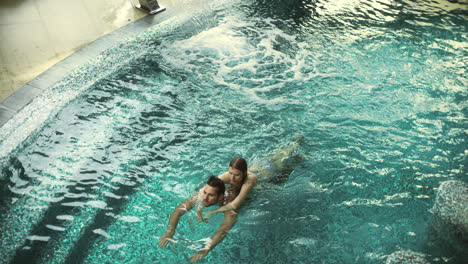 top view of relaxed couple hugging in pool. happy man and woman relax in water