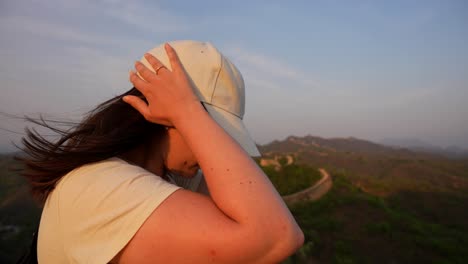 una mujer excursionista admirando la gran muralla china al atardecer en un día de viento