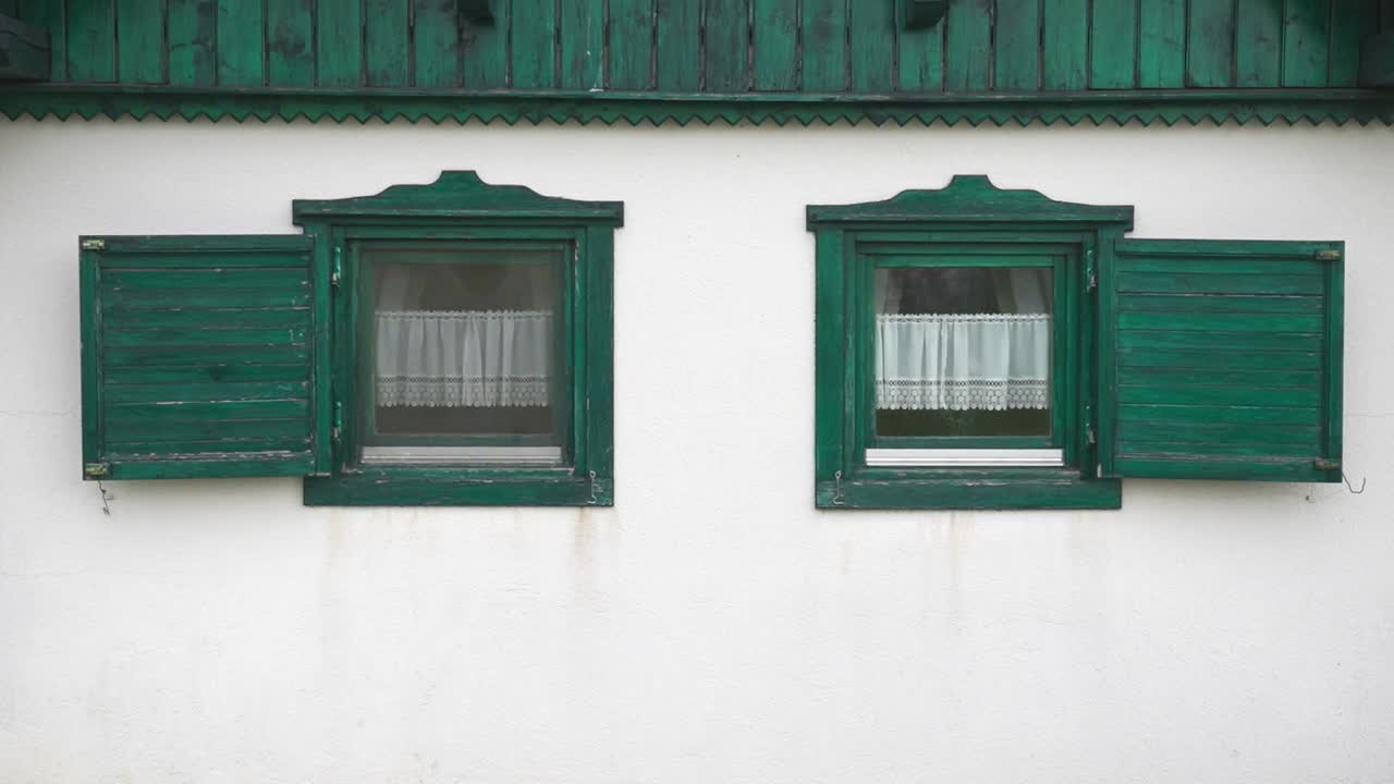 Close-up of two green window shutters on a white wall