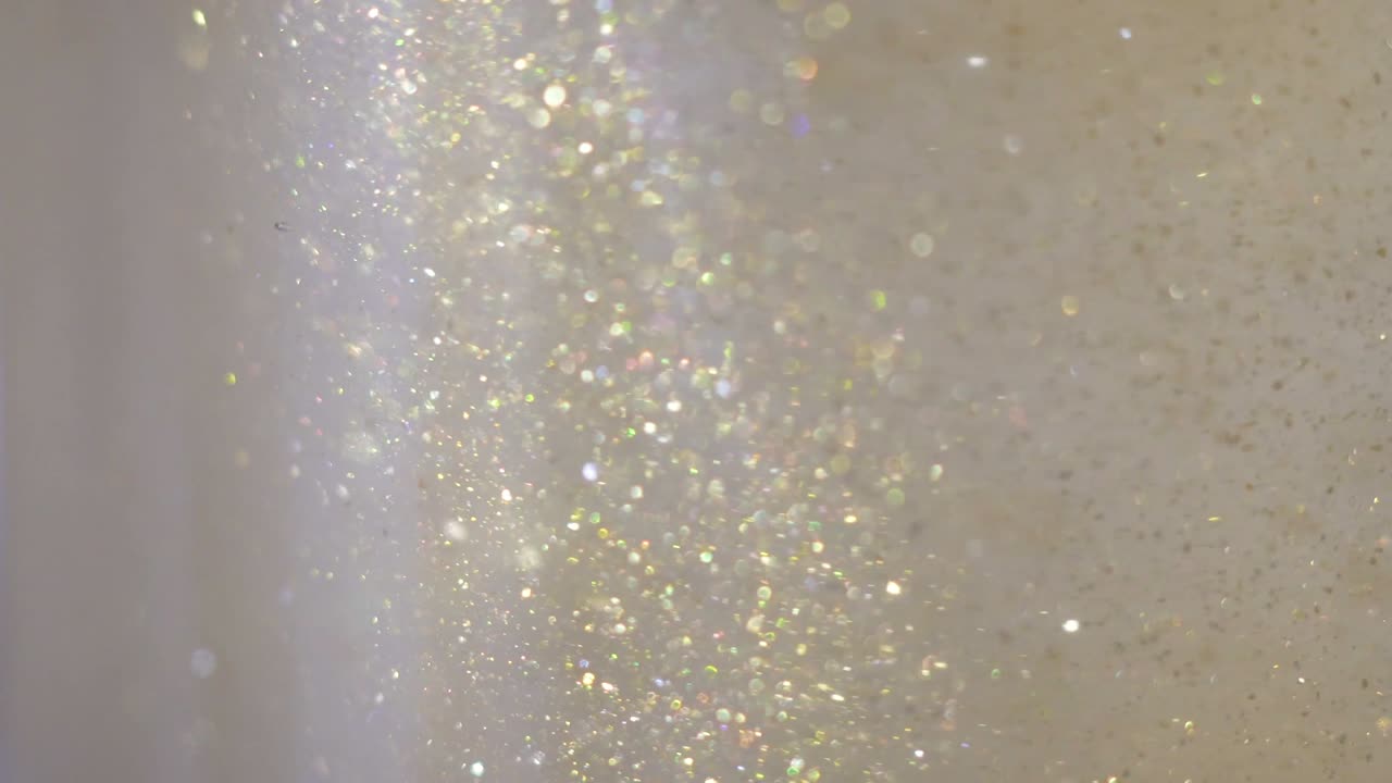 primer plano de brillo flotando en el vodka. pintura dorada de colores mezclándose en el agua. tinta girando bajo el agua. nube de tinta sedosa. vista macro