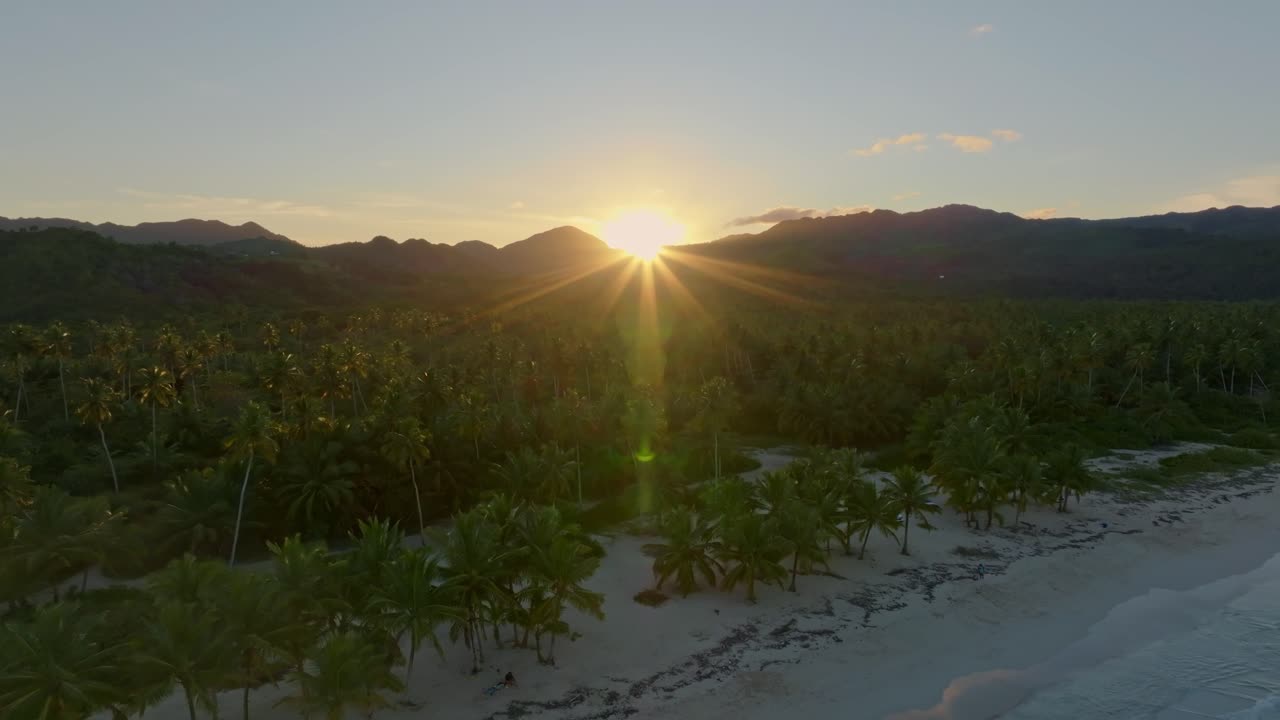 Playa Rincon beach at sunset, bright setting sun in background, backlight, Las Galeras in Dominican Republic, Aerial backward