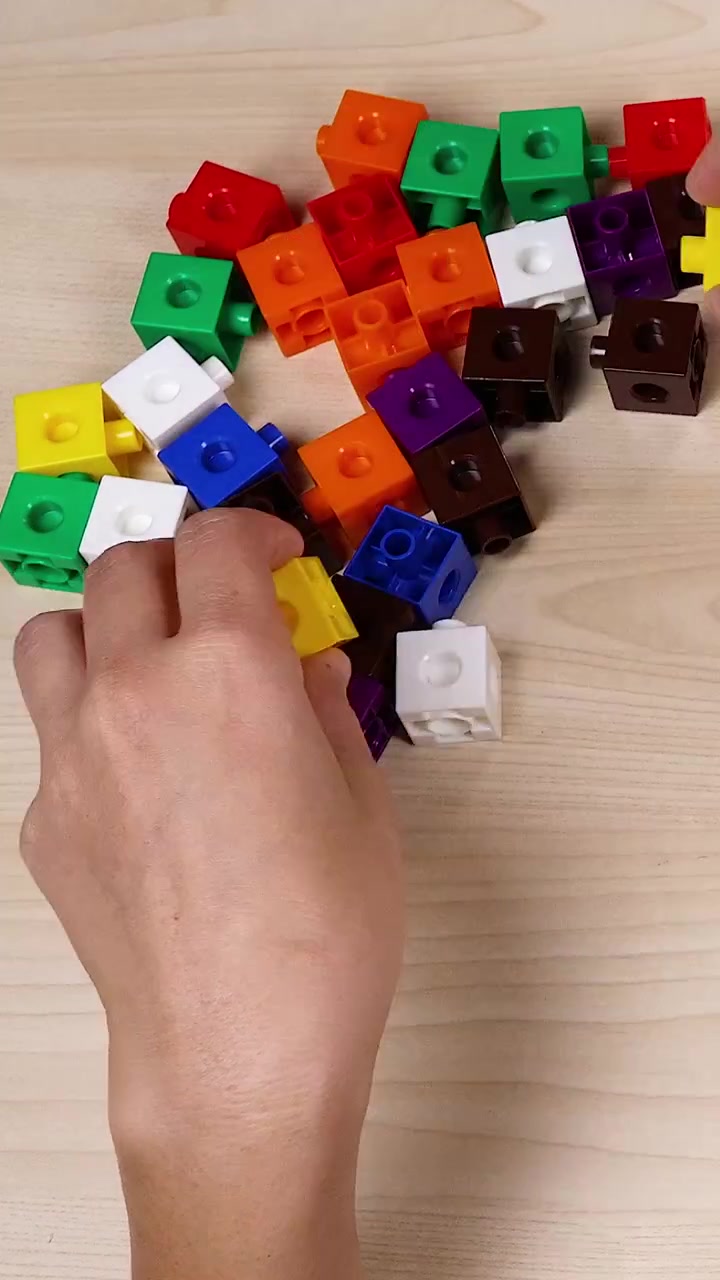 Mani che assemblano cubi colorati a incastro su un tavolo