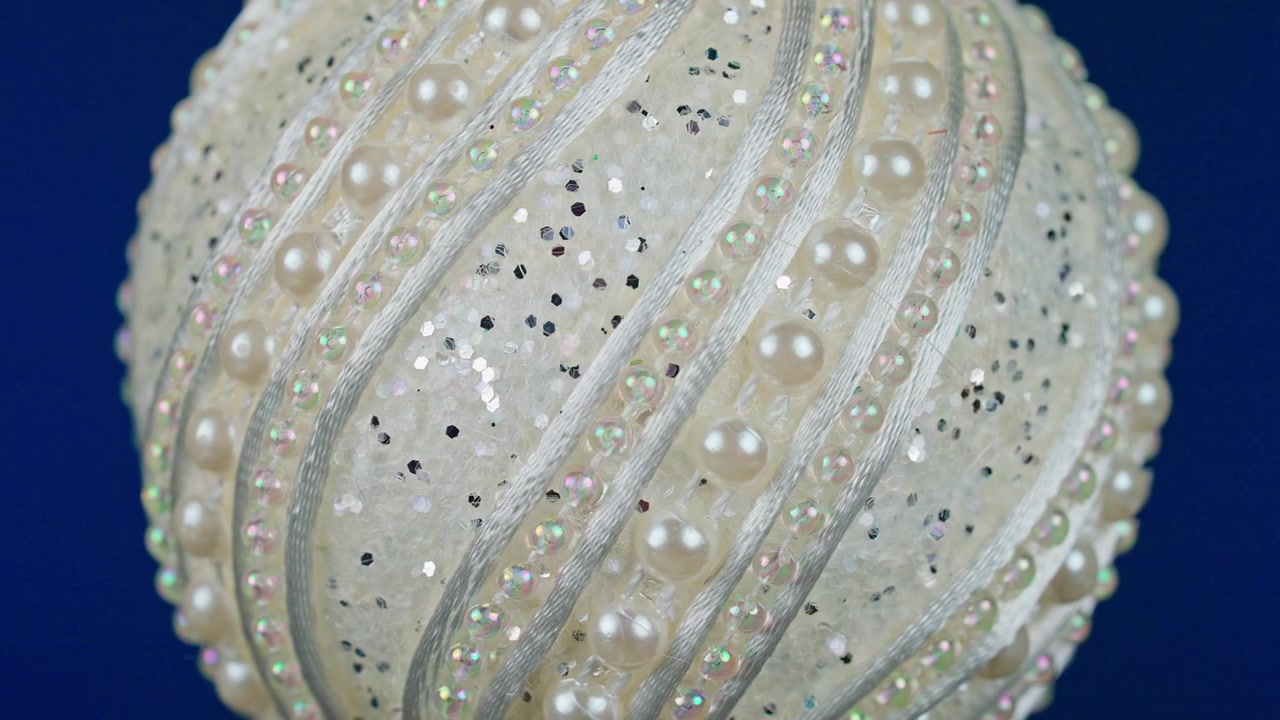 Elegante sfera decorativa bianca con glitter, perle e perline iridescenti.