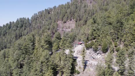 Winding-road-through-dense-forests-leading-to-KPK-from-Nathya-Gali,-Pakistan,-captured-from-an-aerial-perspective