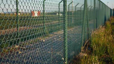 a double chain link fence around a secure facility then the suspicious shadow of a person walking along the fence line