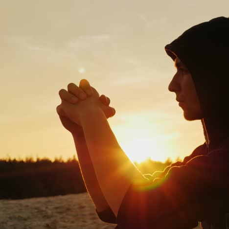 A-young-man-in-a-hood-prays-at-sunset