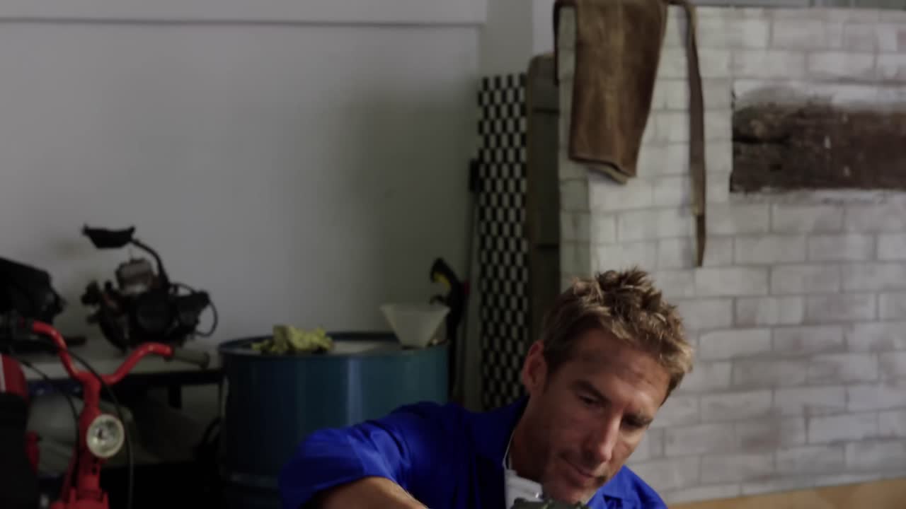 Male mechanic repairing motorbike parts in repair garage 4k
