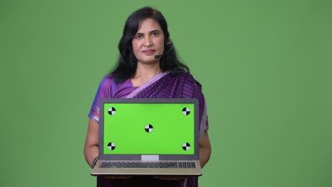 mature beautiful indian woman as call center representative showing laptop