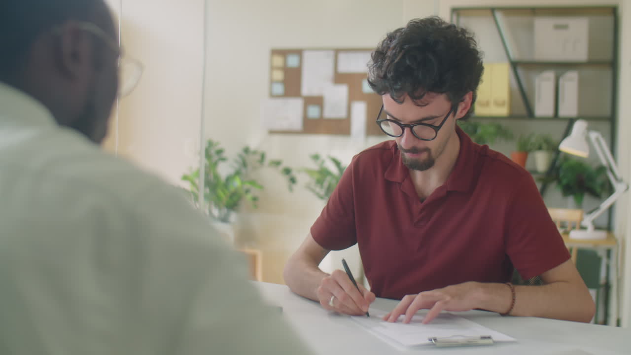 Uomo che firma un contratto e stringe la mano a un partner commerciale in ufficio