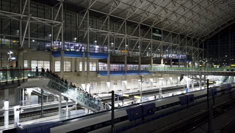 modern train station at night with train and people