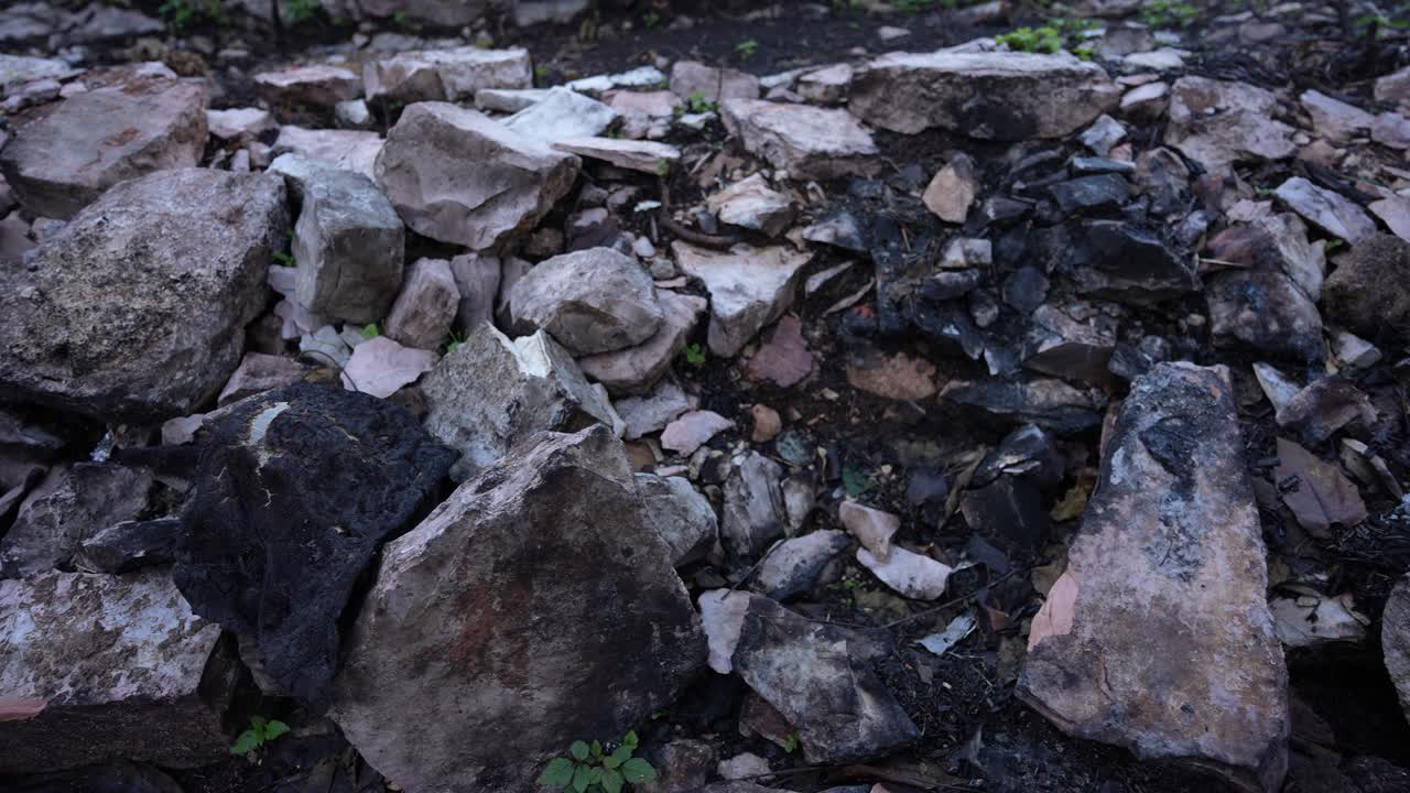 Terra bruciata e centro residenziale danneggiato che illustrano le conseguenze dello sfollamento dovuto alla guerra e della violenza incendiaria domestica.