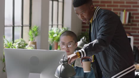 young mixed race man using computer helpful african american team leader sharing ideas pointing at screen training colleague discussing project solution in diverse office