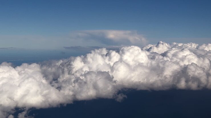 Immersive pilot’s perspective while flying above some storm clouds hanging over a blue color Mediterranean Sea at the Blue Hour
