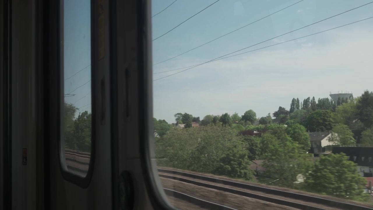 View from inside a moving train showing railway tracks and countryside landscape passing by