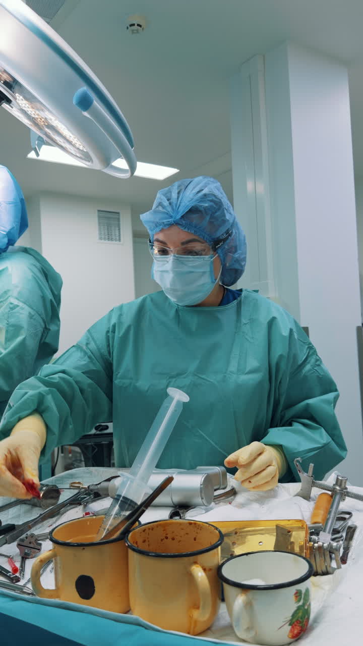 Kyiv, Ukraine, 2 August 2025: Female surgeon preparing instruments on a sterile table in the operating room. A vertical frame captures the professional wearing a mask, cap, and glasses, standing over tools and materials