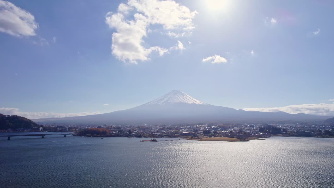 Tilt-up drone footage revealing the majestic Mount Fuji towering over Lake Kawaguchi on a clear winter day