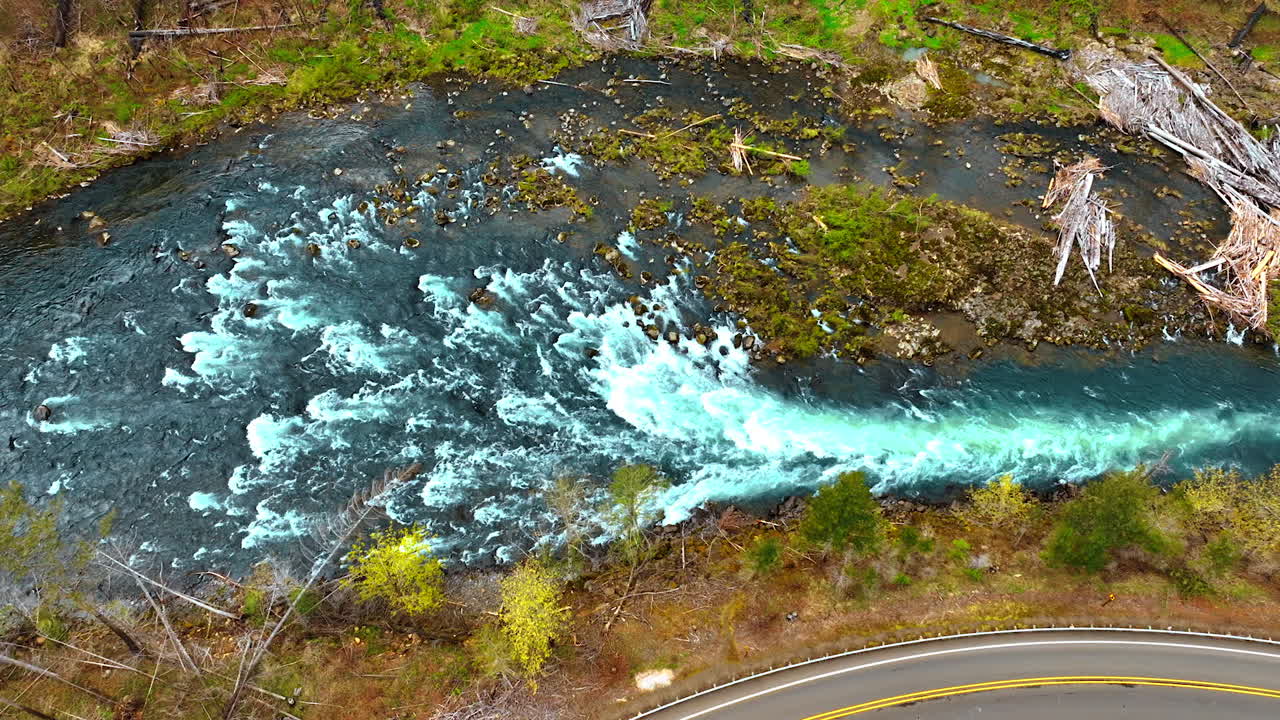 Narrow mountain river with rapids becomes narrower flowing quickly. Top view on the river with banks covered with dry wood.