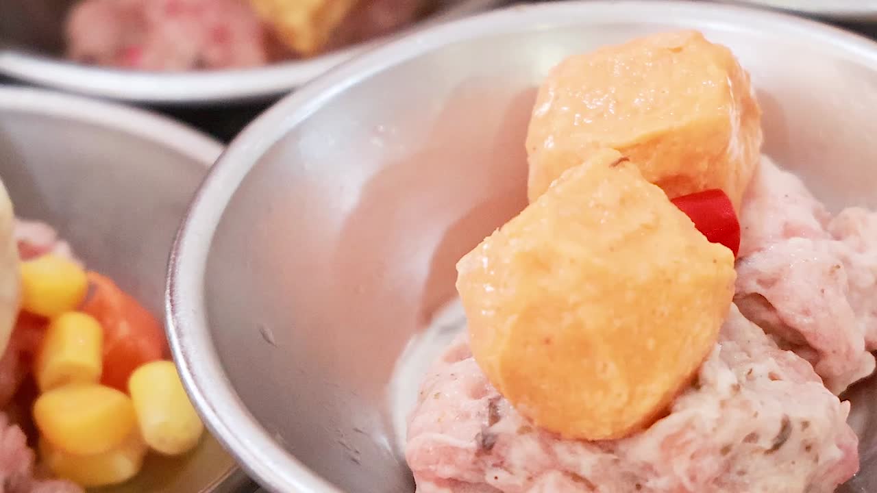 Close-up of various dim sum dishes in metal trays, featuring colorful toppings and diverse ingredients.