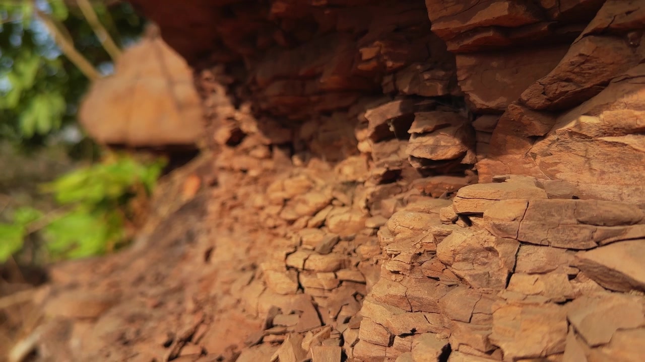Carrellata che scorre attraverso strati di roccia sedimentaria fratturata rivelando intricate texture geologiche, superfici di pietra erose e caratteristiche di erosione naturale su una scogliera scoscesa