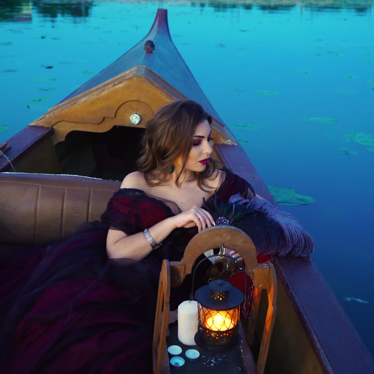 Beautiful woman enjoys the evening nature while traveling by boat at sunset. Portrait of a dreamy female relaxing at sunset sailing alone in gondola