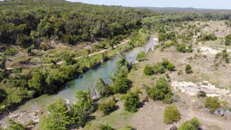 fast pan right to reveal swimming area, flying towards and then up the travel of the river - aerial footage of the blanco river in wimberly, tx