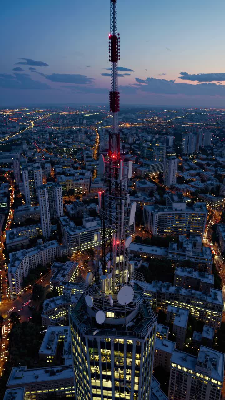 Aerial video shot at dusk capturing a cityscape with a towering skyscraper in the foreground