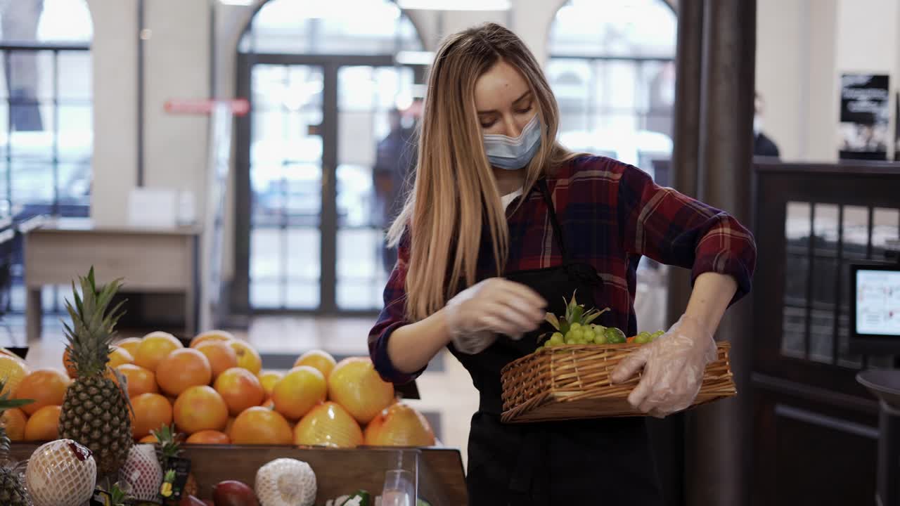 женщина в черном фартуке и маске хранит фрукты в супермаркете